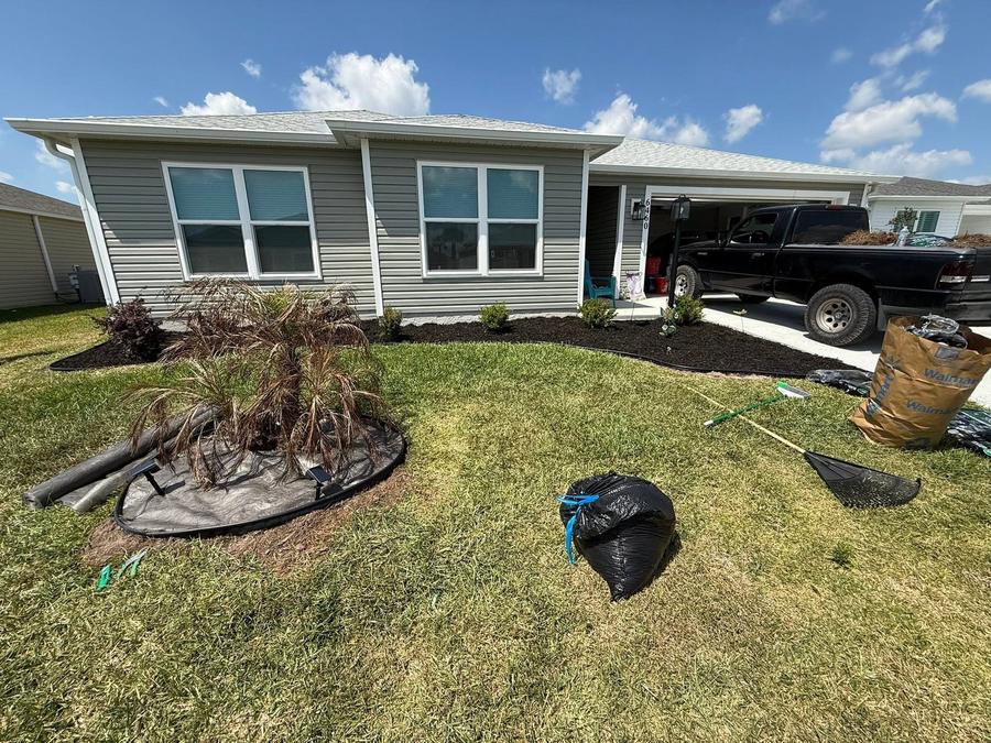 A front yard cleanup in progress, with the truck loaded and debris bagged beside a freshly dug bed